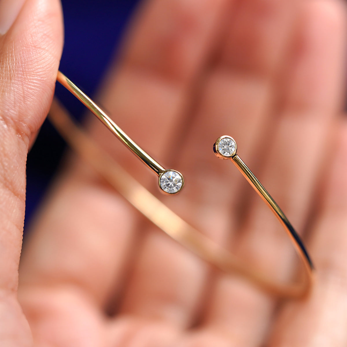 A model holding a 14k gold diamond bypass bangle bracelet to show the gap in the bangle