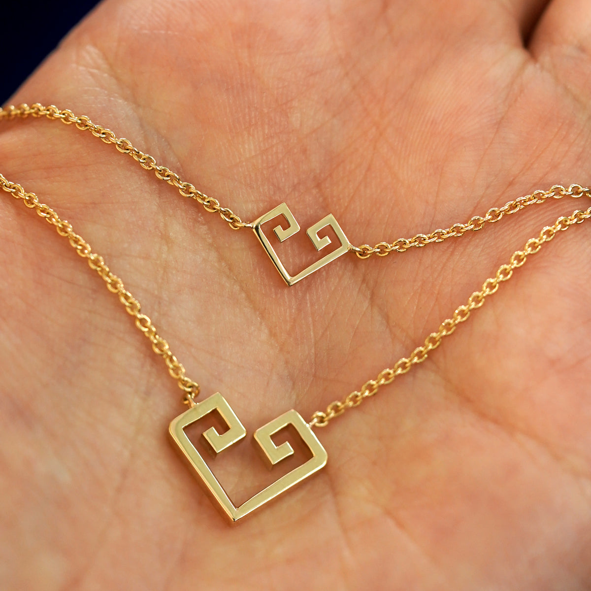 A Geometric heart bracelet and large necklace layered on a model's palm