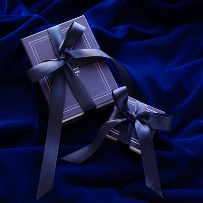 An Automic Gold Ring Box and Book Box both gift wrapped in a blue ribbon