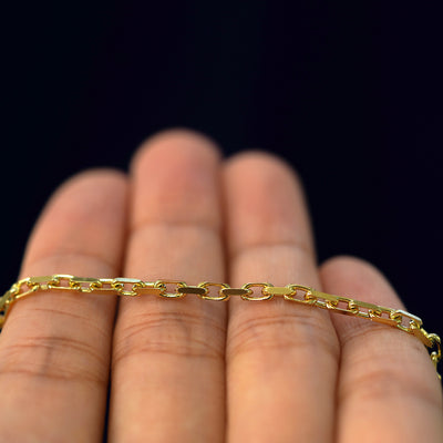 A yellow gold Anchor Bracelet resting on a model's fingers