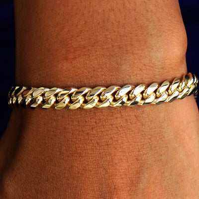 Close up view of a model's wrist wearing a solid 14k yellow gold Miami Cuban Bracelet