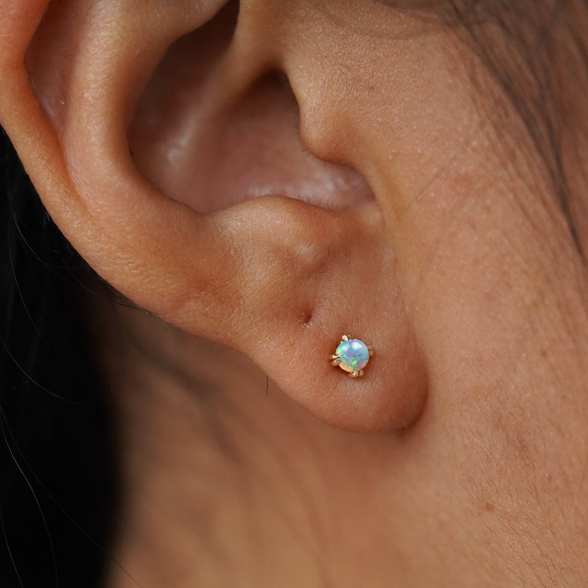 Close up view of a model's ear wearing a yellow gold Opal Flat Back Earring