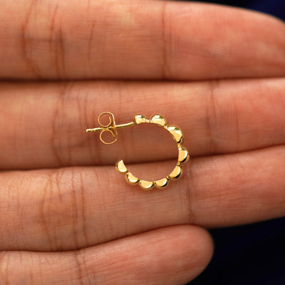 A Graduated Puffy Beaded Hoop laying sideways on a model's fingertips to show the details of the post and the side of the hoop