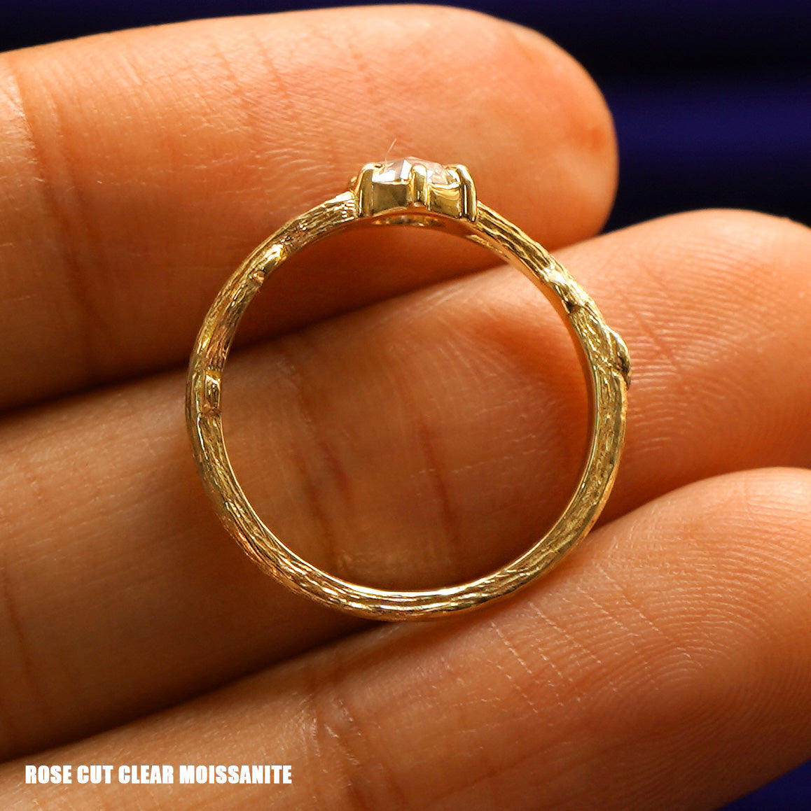 A yellow gold Rose cut clear Moissanite Branches Ring in a model's hand showing the claw prong detailing and the whole ring
