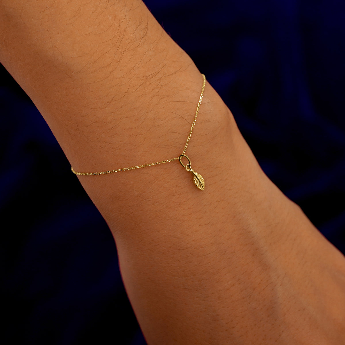 A model's wrist wearing a yellow gold Leaf Charm on a Cable Bracelet