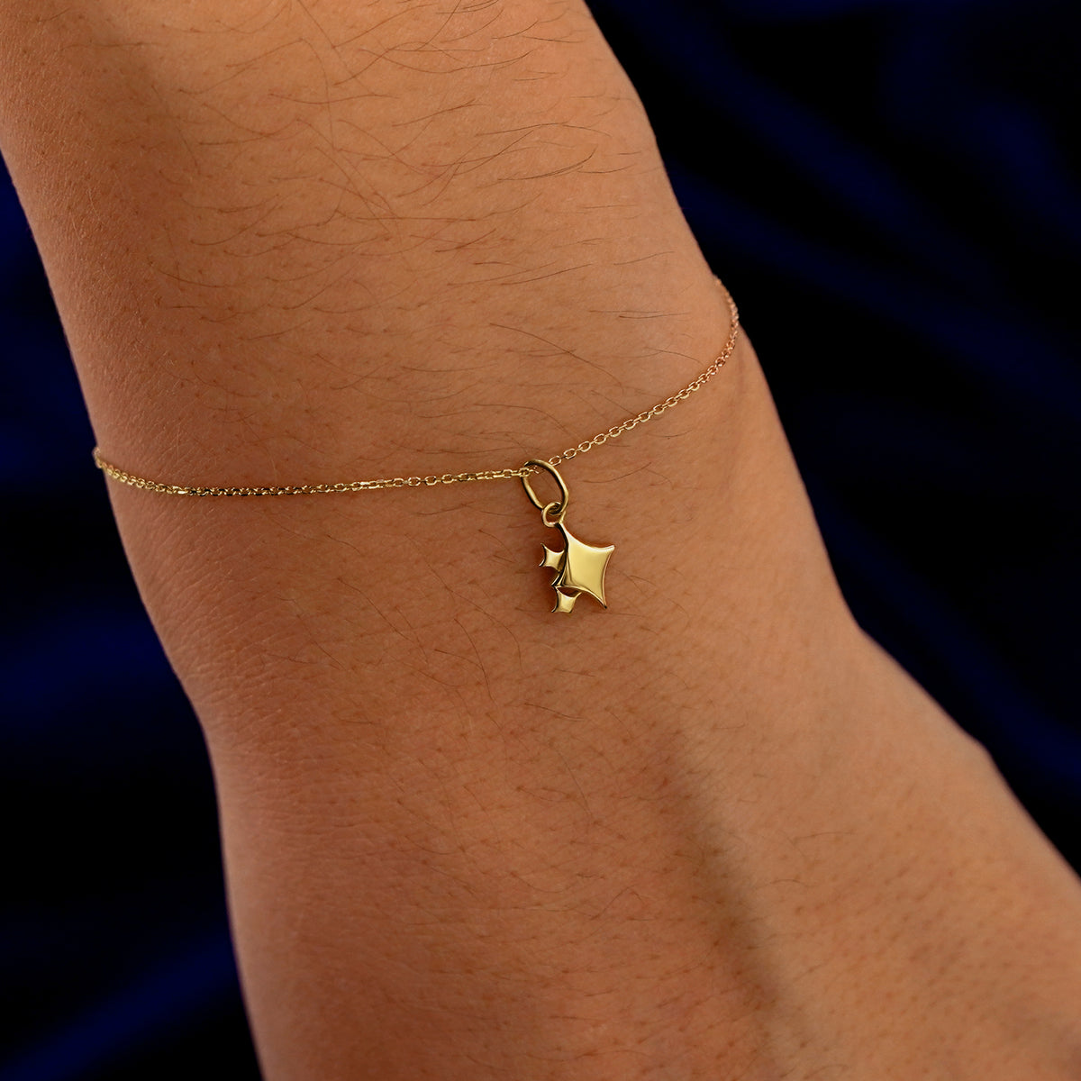 A model's wrist wearing a yellow gold Sparkly Star Emoji Charm on a Cable Bracelet