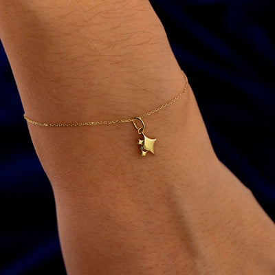 A model's wrist wearing a yellow gold Sparkly Star Emoji Charm on a Cable Bracelet