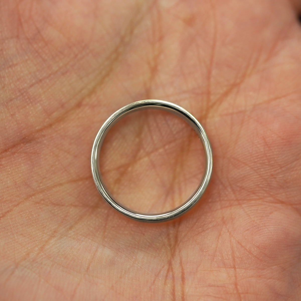 A champagne and rose gold Inlay Band in a model's palm showing the thickness of the band