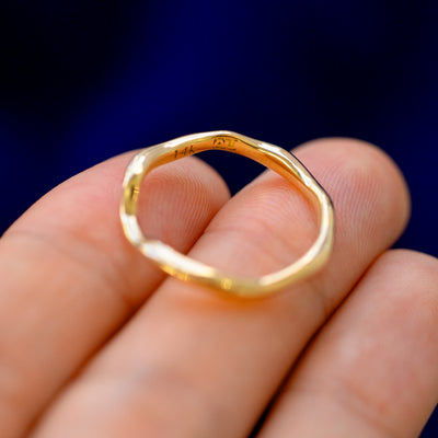 A solid gold Thin Liquid Band on a model's fingertips showing all the curves in the band