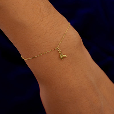 A model's wrist wearing a yellow gold 3 Leaves Charm on a Cable Bracelet