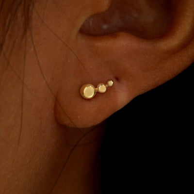Close up view of a model's ear wearing a yellow gold Graduated Ball Earring