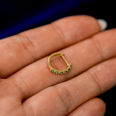 A small Light Green Lab Diamond huggie hoop earring on a models fingers