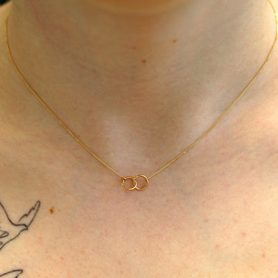 A model's neck wearing a solid gold Mini Bound Together Necklace