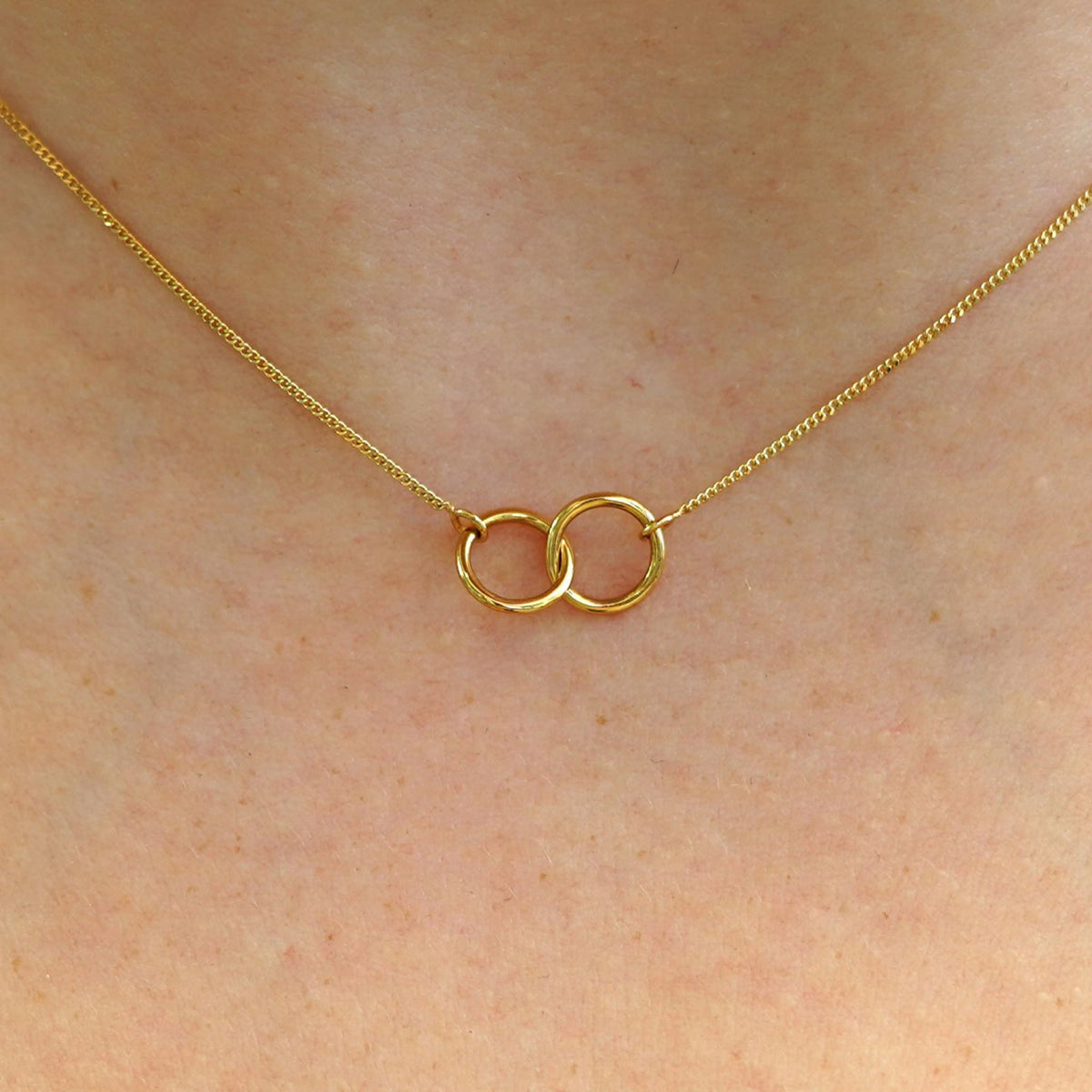 Close up view of a model's neck wearing a solid gold Mini Bound Together Necklace