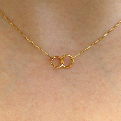 Close up view of a model's neck wearing a solid gold Mini Bound Together Necklace
