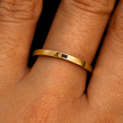 A 14k yellow gold Flush Set Black Baguette Diamond Ring on a model's finger