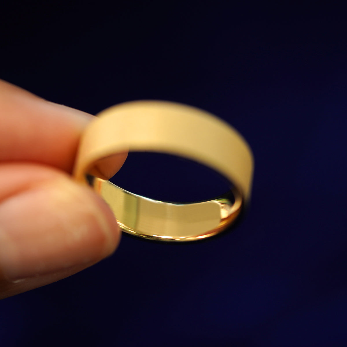 A model holding a Industrial Stardust Band tilted to show the inside of the ring