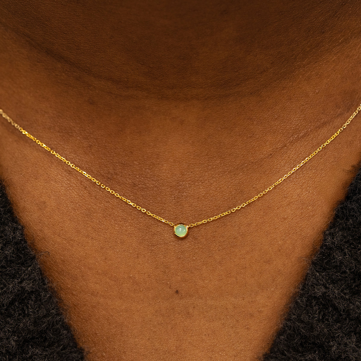 Close up view of a model neck wearing a 14k yellow gold Bezel set Jade gemstone necklace 