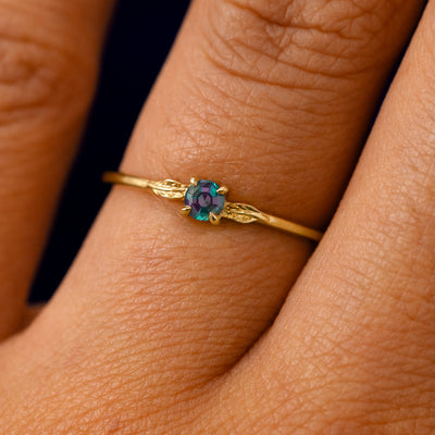 A solid 14k yellow gold Lab Alexandrite Gemstone Two Leaf Ring on a model's finger