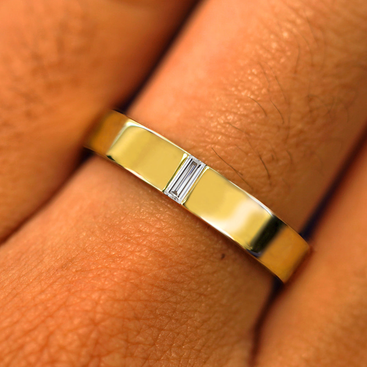 Close up view of a model's hand wearing a solid yellow gold Clear Diamond Band