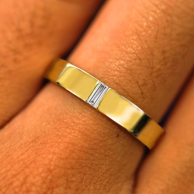 Close up view of a model's hand wearing a solid yellow gold Clear Diamond Band