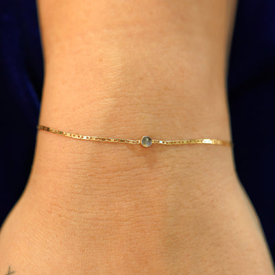 A model's wrist wearing a solid 14k yellow gold Labradorite Bracelet