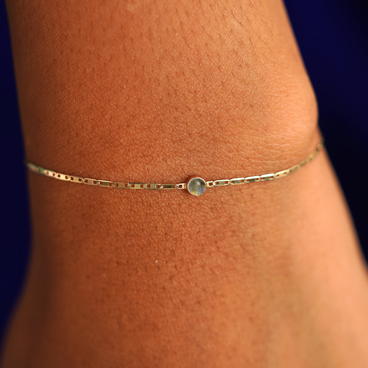 A model's wrist wearing a 14 karat yellow gold Labradorite Bracelet