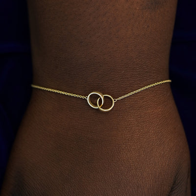 A model's wrist wearing a solid gold Bound Together Bracelet