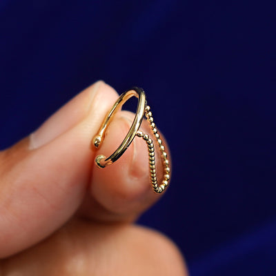 A model holding a yellow gold Line Cuff with Chain between two fingertips