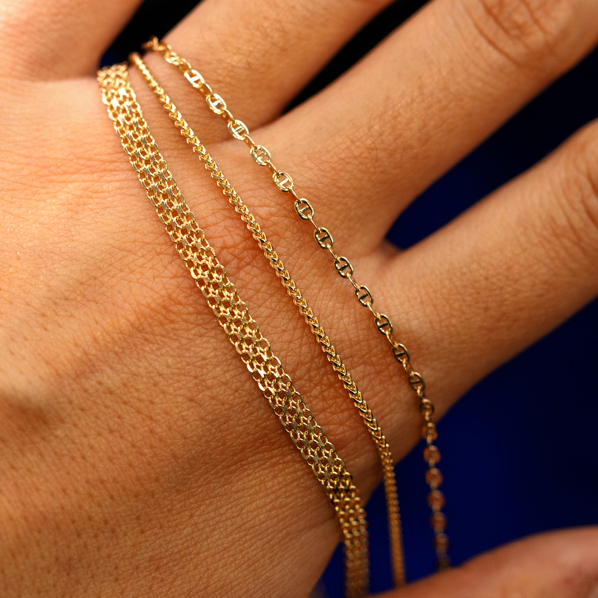 A models hand holding a  Bismark Bracelet, a Mini Franco Bracelet, and a Flat Mariner Bracelet
