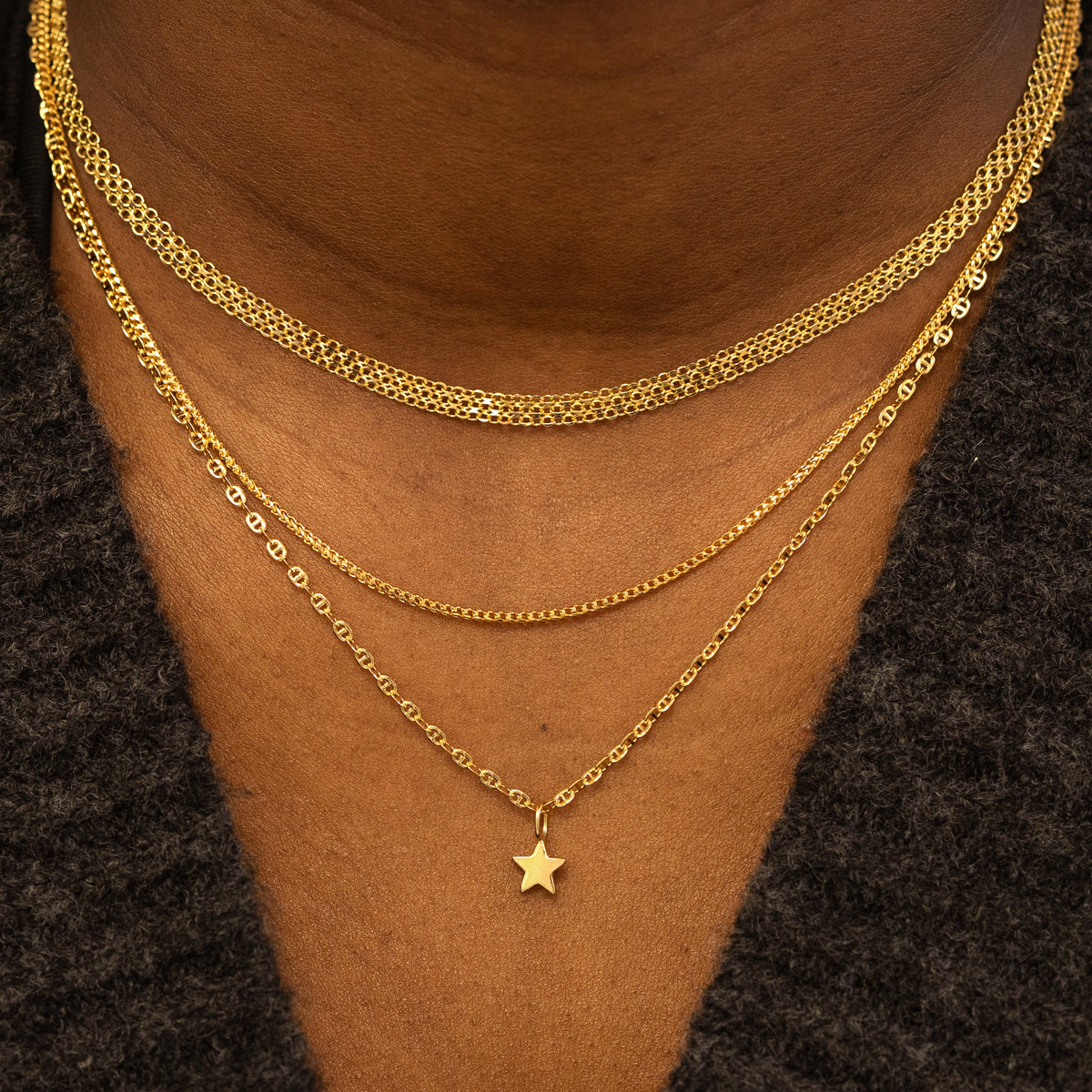 A models neck wearing a Bismark Chain, a Mini Franco Chain, and a Flat Mariner Chain with a Star Charm, layered