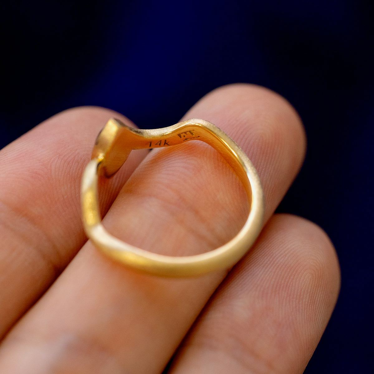 A solid gold marquise cabochon salt and pepper diamond ring on a model's fingertips showing the inside of the band