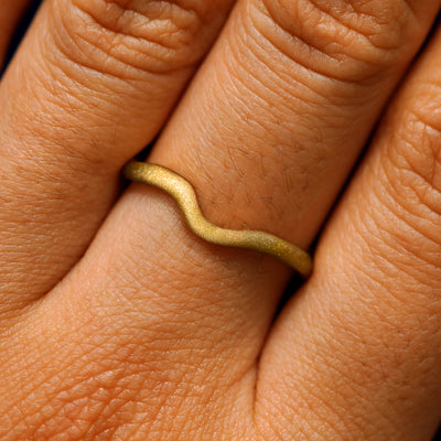 Close up view of a model's hand wearing a matte thin liquid band
