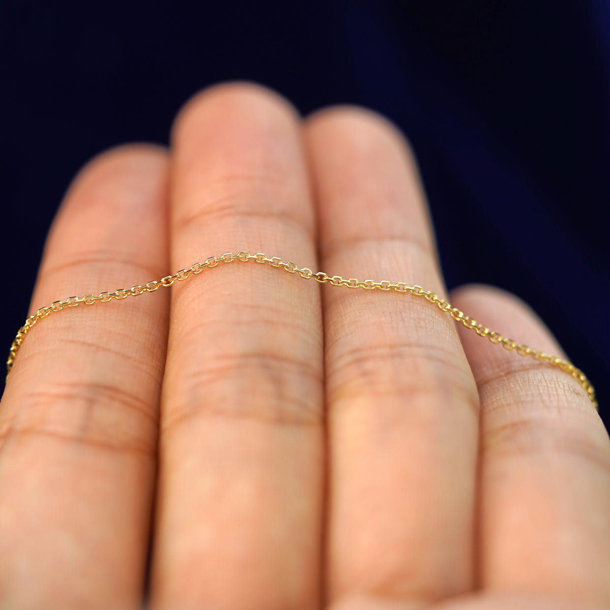 A yellow gold Medium Cable Chain resting on a model's fingers
