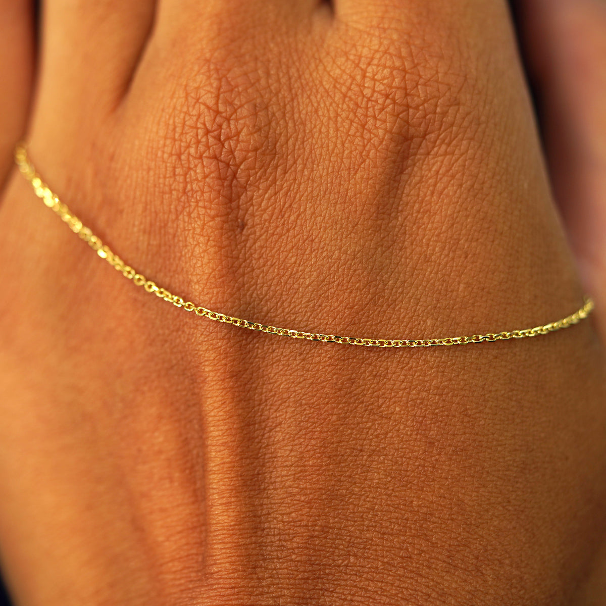 A solid gold Medium Cable Chain resting on the back of a model's hand