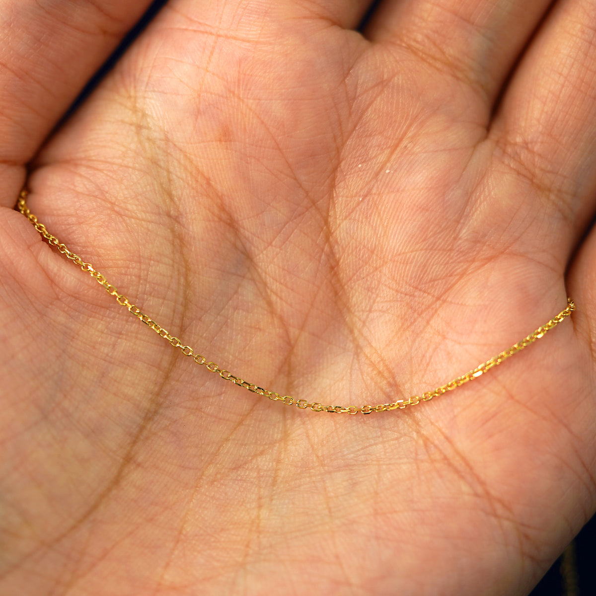 A yellow gold Medium Cable Chain draped on a model's palm