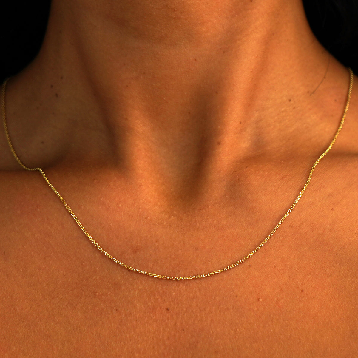 A model's neck wearing a solid 14k yellow gold Medium Cable Chain