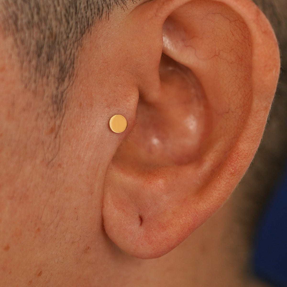 A model's ear wearing a 14k yellow gold Medium Circle Flatback in a tragus piercing