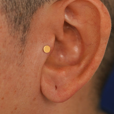 A model's ear wearing a 14k yellow gold Medium Circle Flatback in a tragus piercing