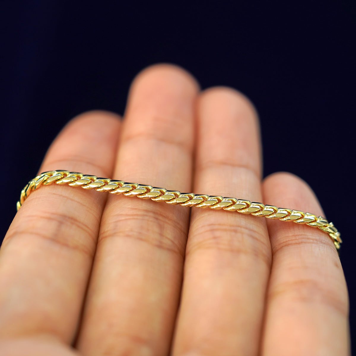 A yellow gold Medium Miami Bracelet resting on a model's fingers