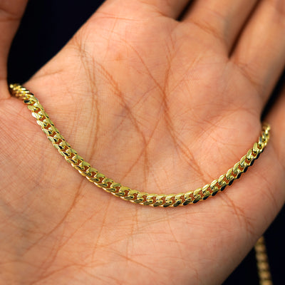 A yellow gold Medium Miami Bracelet draped on a model's palm