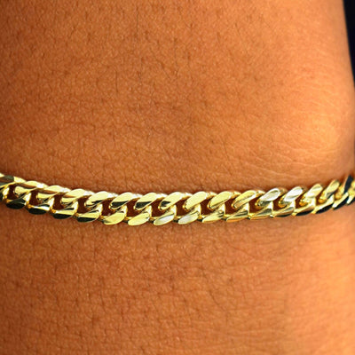 Close up view of a model's wrist wearing a 14k yellow gold Medium Miami Bracelet