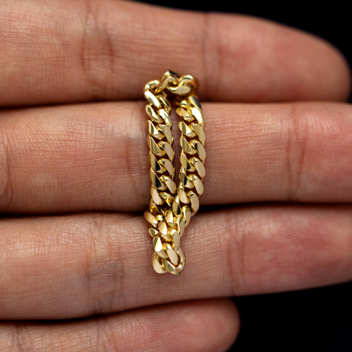 A yellow gold Medium Miami Ring laying flat in a models hand to show the flexibility of the chain