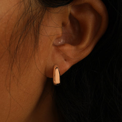 A model's ear wearing a rose gold Medium Teardrop Huggie Hoop and a Small Teardrop Huggie Hoop in two piercings