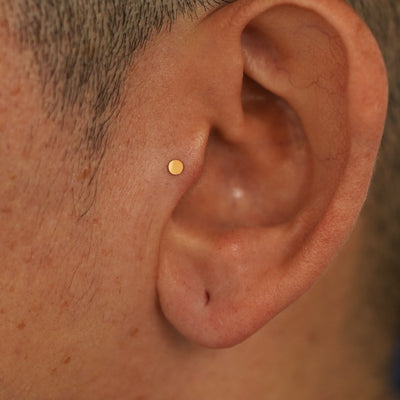 A model's ear wearing a 14k yellow gold Mini Circle Flatback in a tragus piercing