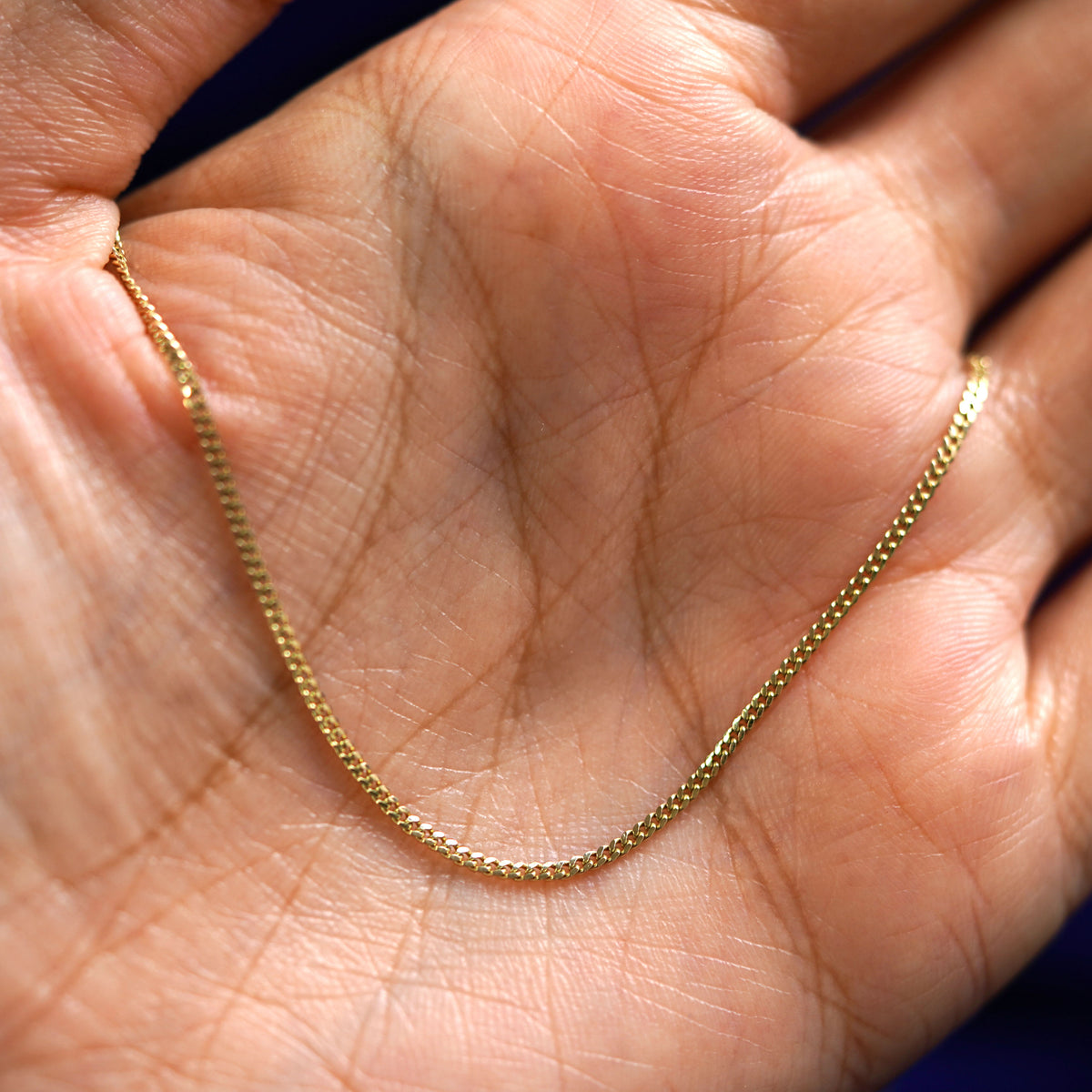 A yellow gold Mini Miami Chain draped on a model's palm