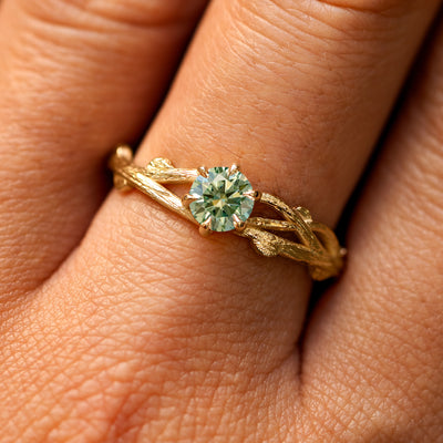 Close up view of a model's fingers wearing a 14k yellow gold Mint Moissanite Branches Ring