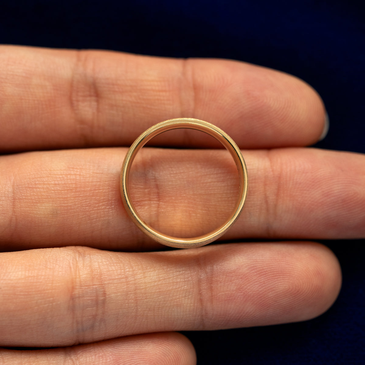 A yellow gold Mix Matte Band in a model's hand showing the thickness of the band