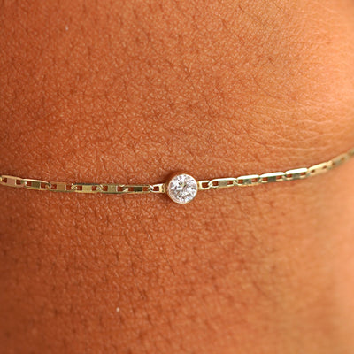 Close up view of a models wrist wearing 14k yellow gold Moissanite Bracelet