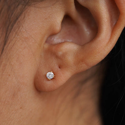Close up view of a model's ear wearing a 14k yellow gold Moissanite Stud Earring